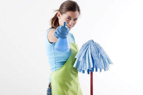Cleaner using safe methods in a Hackney home with protective equipment